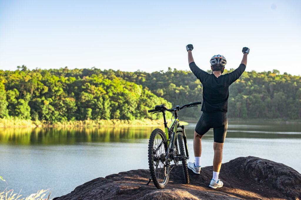 A Mountain Bike cyclist standing on top of a mountain with a bicycle.