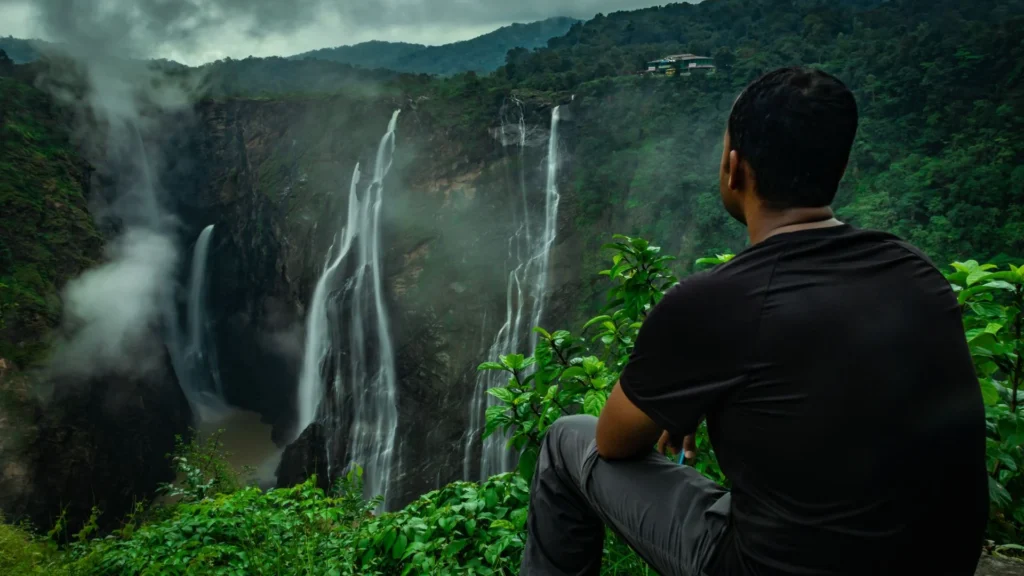 man sitting and watching waterfall Chikmagalur for Weather and Scenic Views